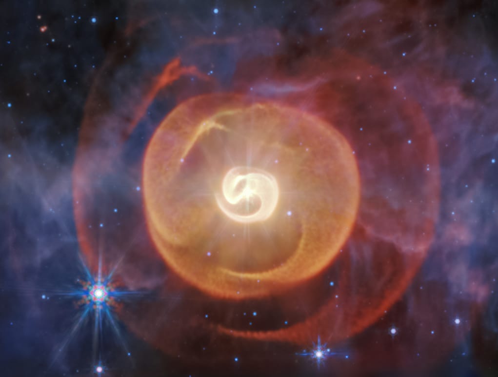 a photo captured by the James Webb Space Telescope of four coiled shells of dust around a pair of Wolf-Rayet stars known as Apep