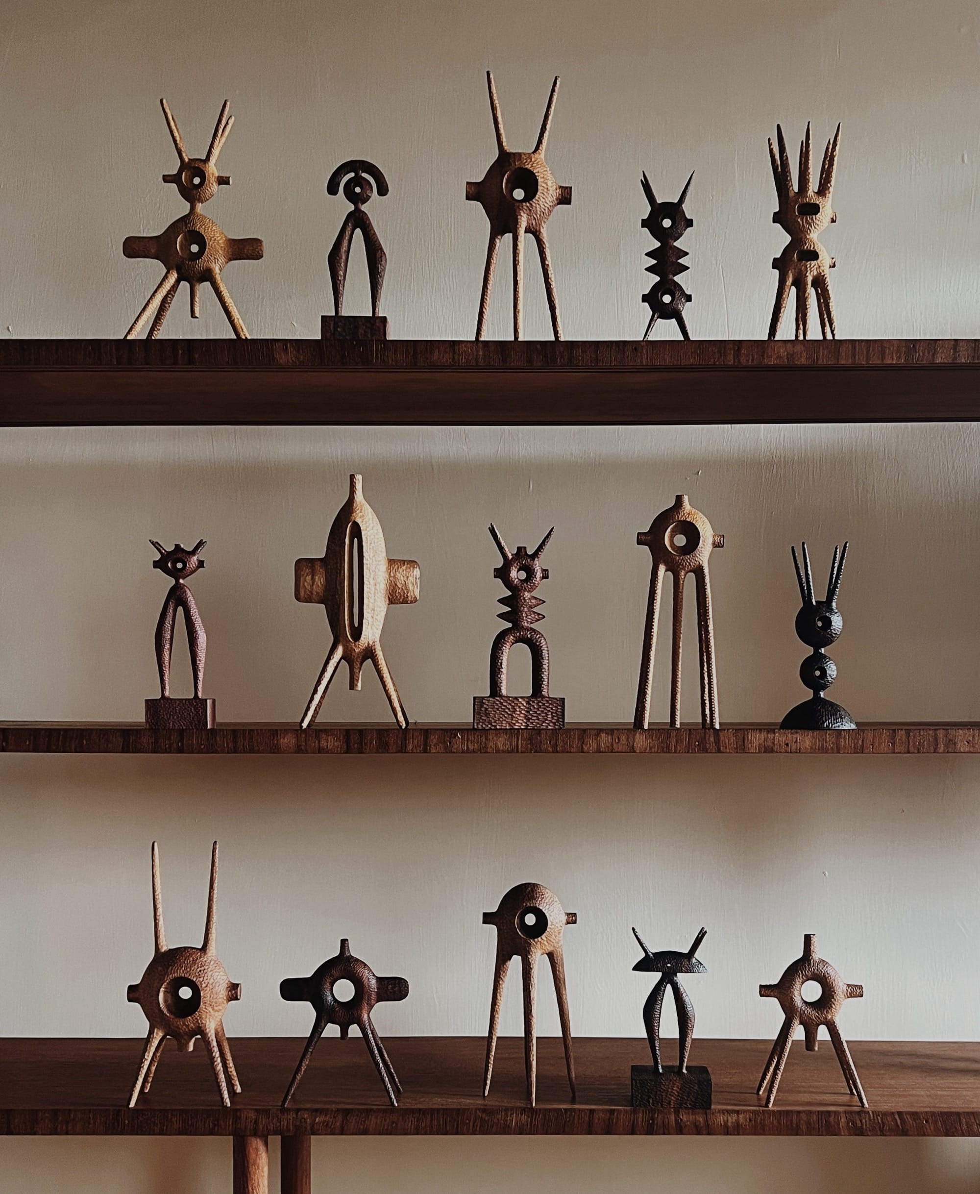 a collection of small, abstract, spindly wooden sculptures on wooden shelves