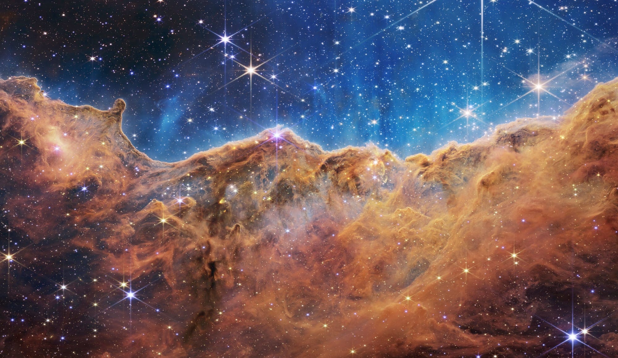 a galactic image of brown-orange dust and a star studded blue expanse
