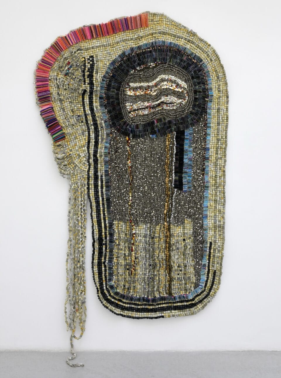 an abstract wall-installed artwork by Moffatt Takadiwa made from computer keyboard keys, combs, toothbrush heads, buttons, and pieces of nail polish applicators