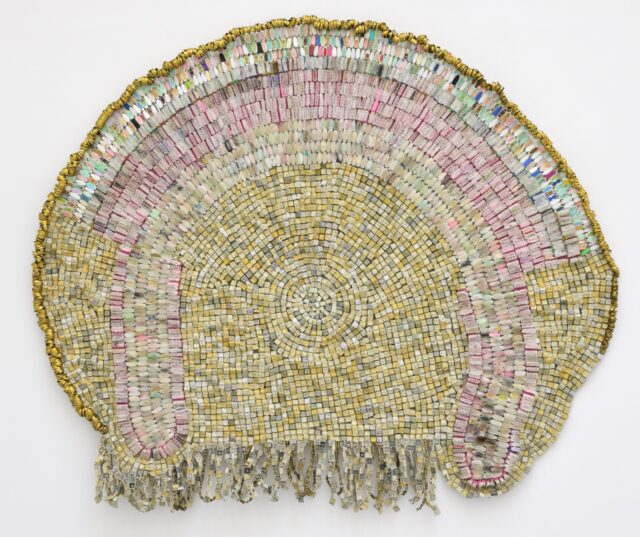 an abstract wall-installed artwork by Moffatt Takadiwa made from computer keyboard keys, combs, toothbrush heads, and metal pieces