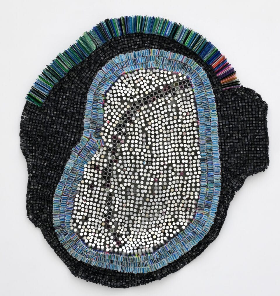 an abstract wall-installed artwork by Moffatt Takadiwa made from computer keyboard keys, combs, toothbrush heads, and pieces of nail polish applicators